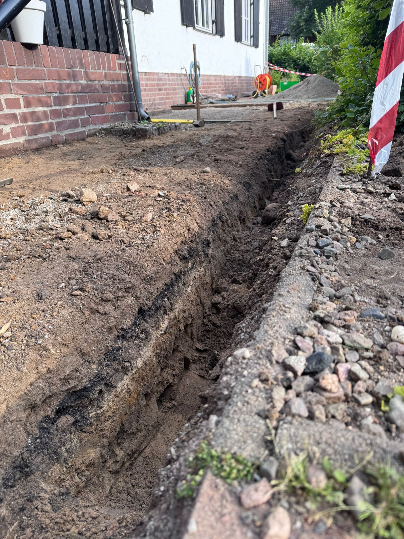 Ausgehobener Drainagegraben auf der Gartenseite – Versickerungspunkt für das abgeleitete Regenwasser